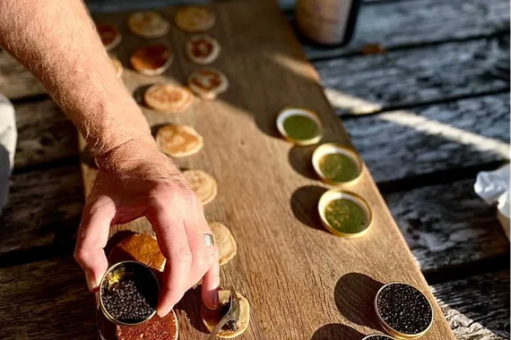 Hænder anretter små retter på et træbræt