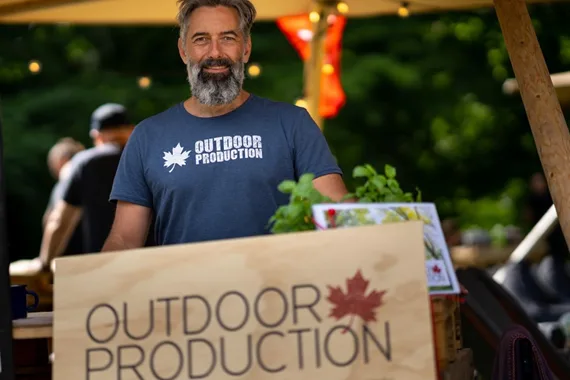 Instruktør fra Outdoor Production med en kasse grøntsager